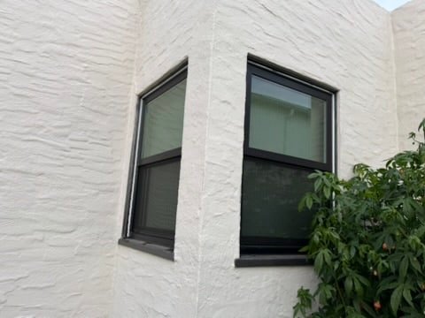 Black aluminum corner windows on white stucco home, East Bay