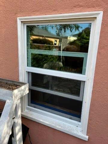 New double-hung vinyl window on stucco home exterior, East Bay