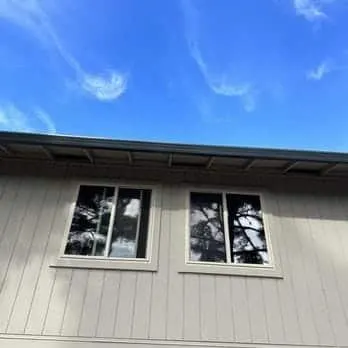 Two new vinyl windows on gray home exterior with blue sky, East Bay