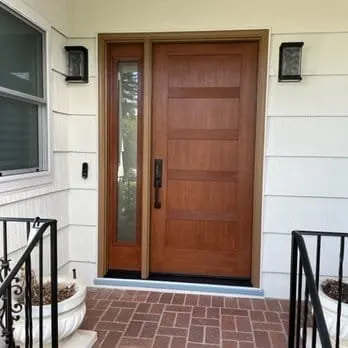 Solid wood entry door with glass sidelite on white home with porch, East Bay