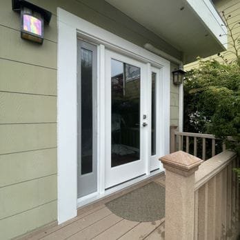 New white entry door with glass sidelite on green home, East Bay