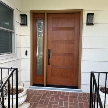 Solid wood entry door with glass sidelite on white porch home, East Bay